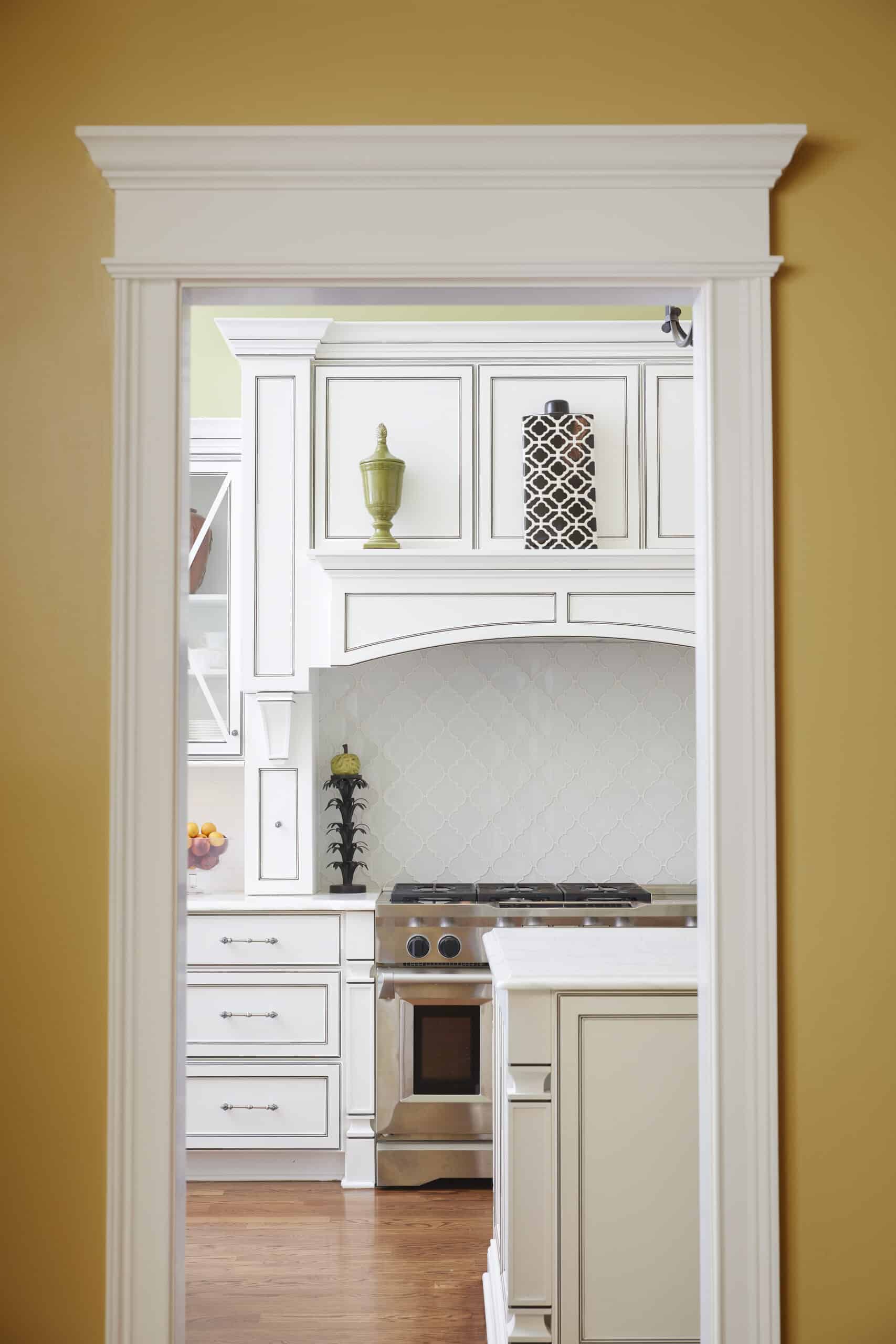 White kitchen with custom cabinetry, stainless steel range and gray patterned tile backsplash