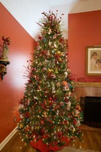 Tall Christmas tree decorated with colorful ornaments, red berries and twinkling lights