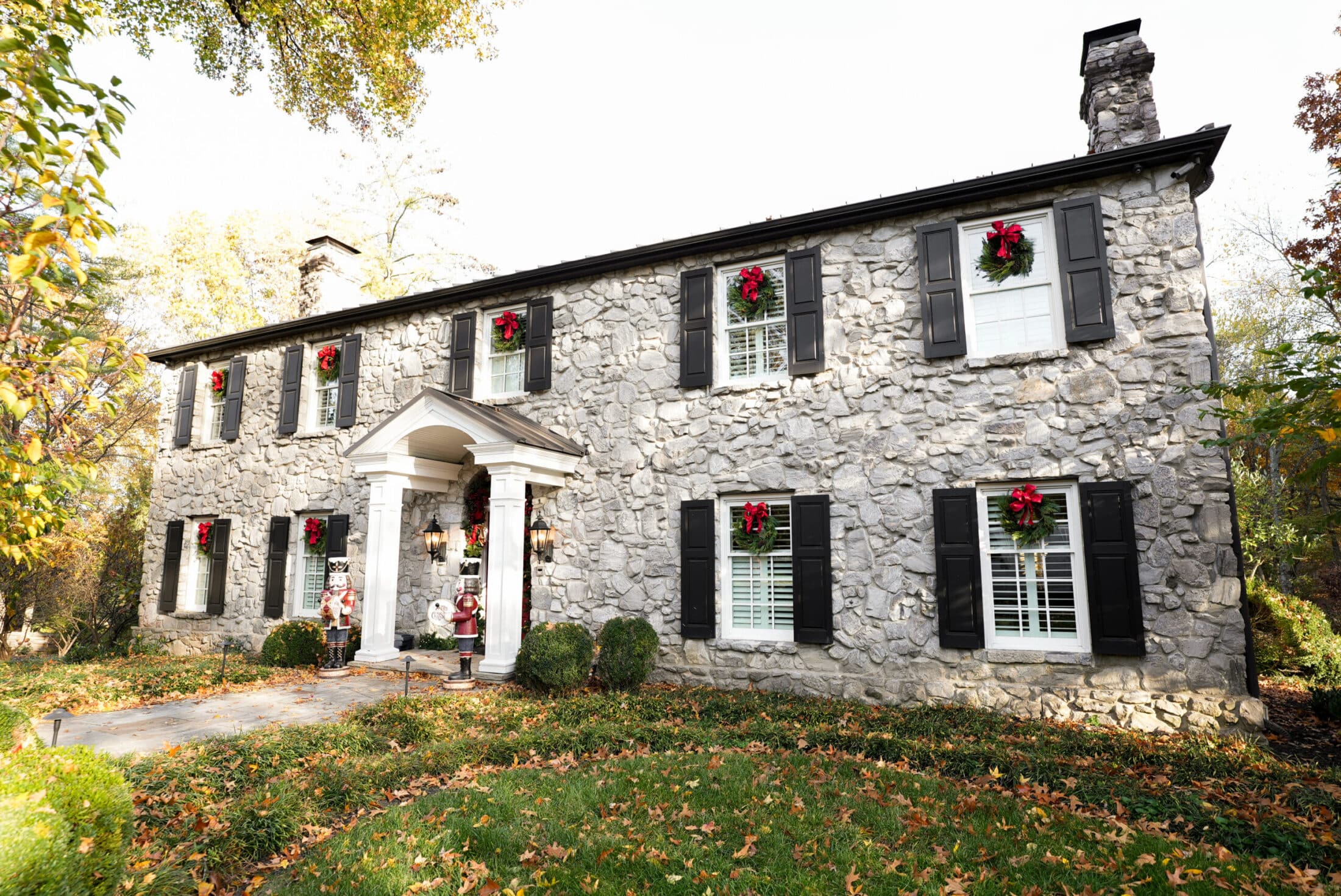Stone home exterior decorated with Christmas wreaths and red bows