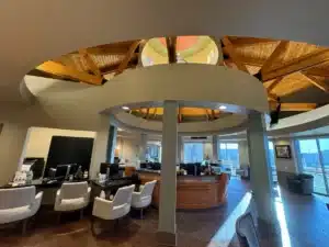 Commercial reception area with circular desk, curved architectural details and exposed wood ceiling beams.